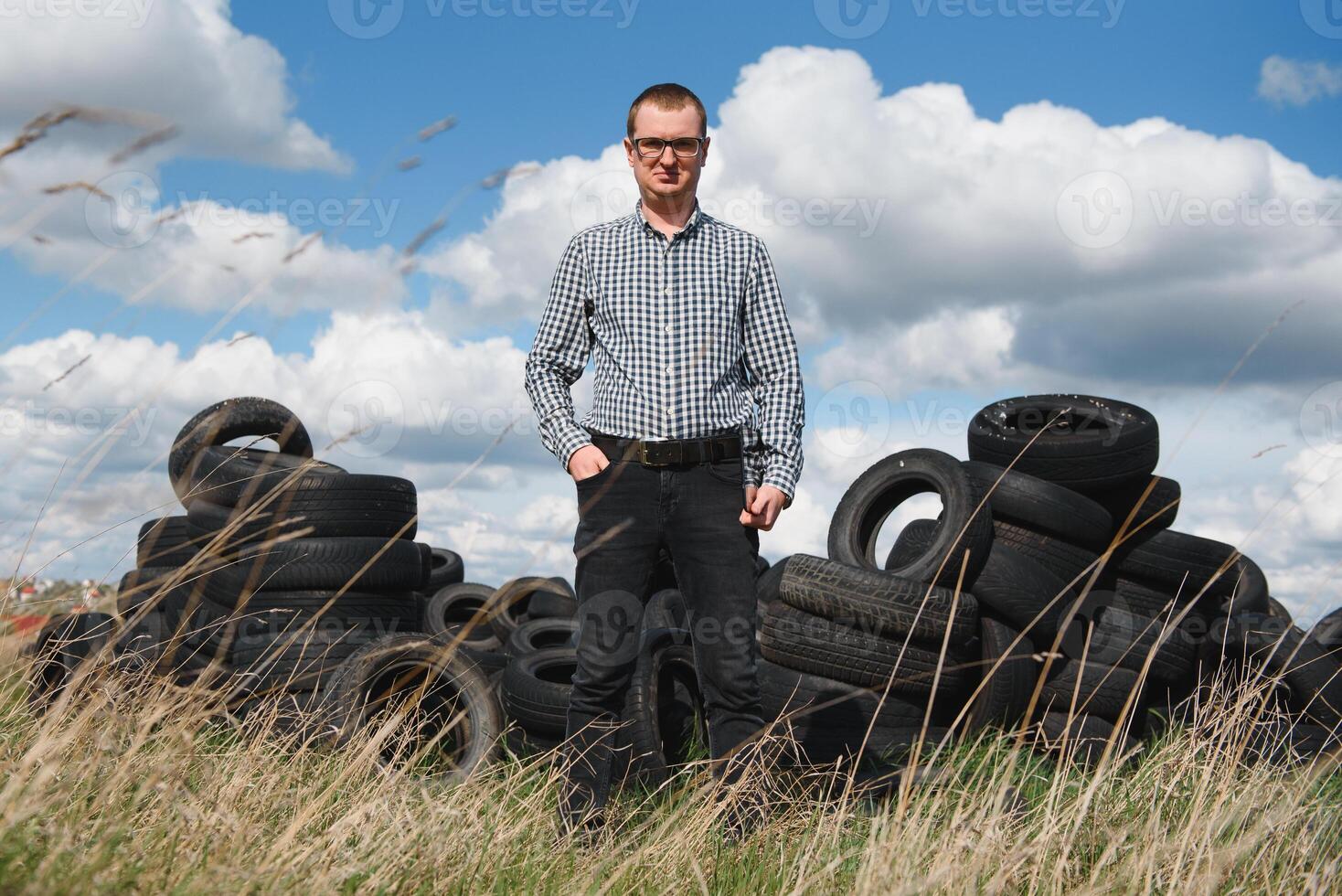 éco-activiste à le décharge de utilisé voiture pneus calcule environnement dommage. la nature préservation concept photo