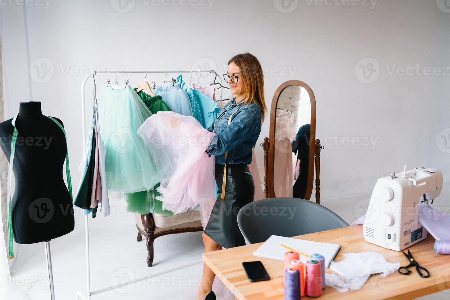 attrayant femelle mode designer est travail dans sa atelier. élégant femme dans processus de création Nouveau vêtements collection. photo