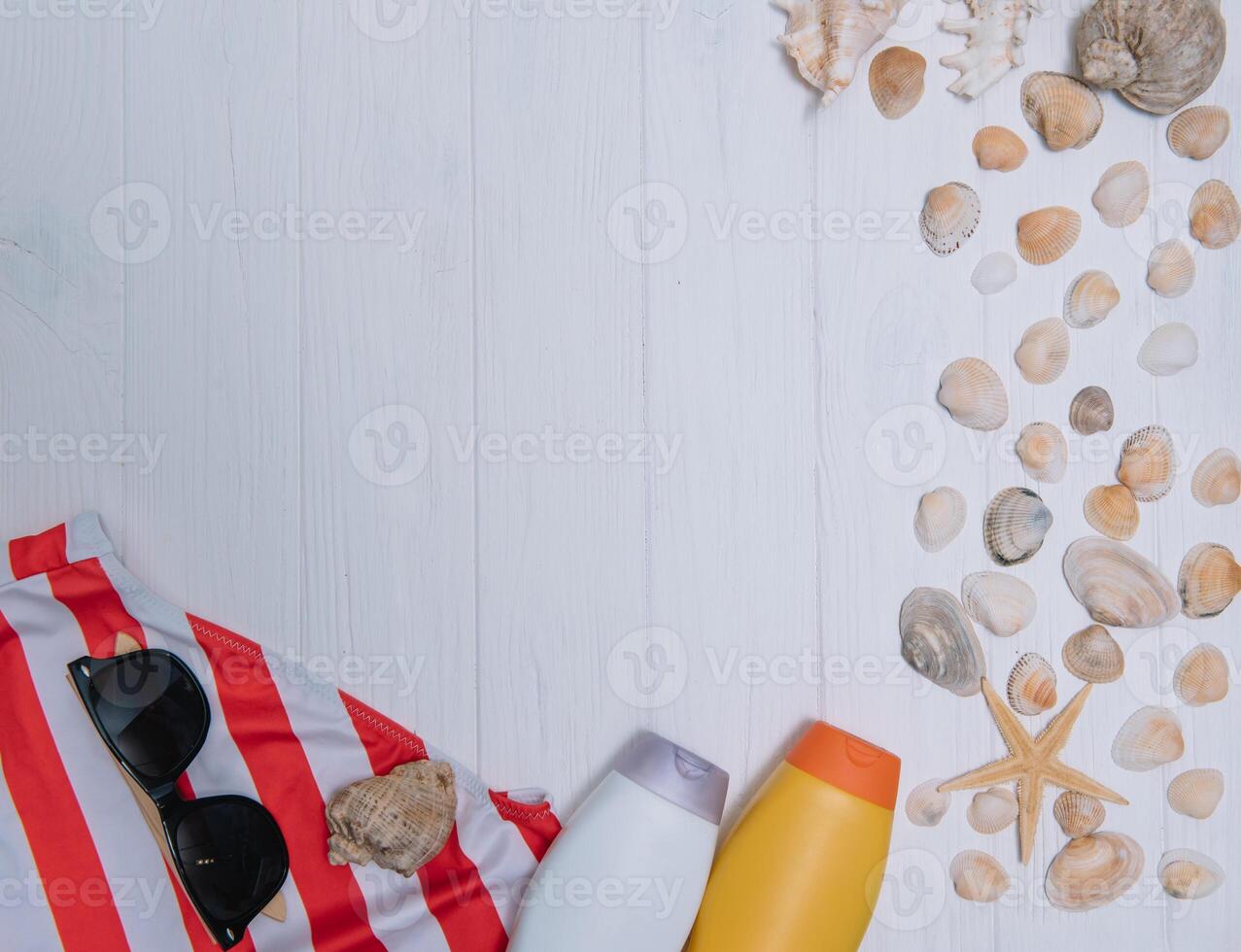 plage accessoires. serviette, tongs, étoile de mer, bateau et des lunettes de soleil sur en bois Contexte. Haut vue avec copie espace. ensoleillé tonique photo