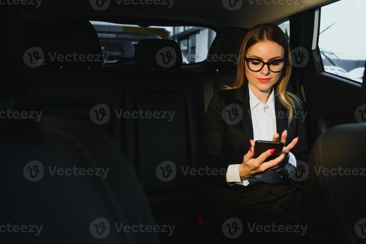 certains Trier de intéressant information. intelligent femme d'affaires est assis à banquette arrière de le luxe voiture avec noir intérieur. photo