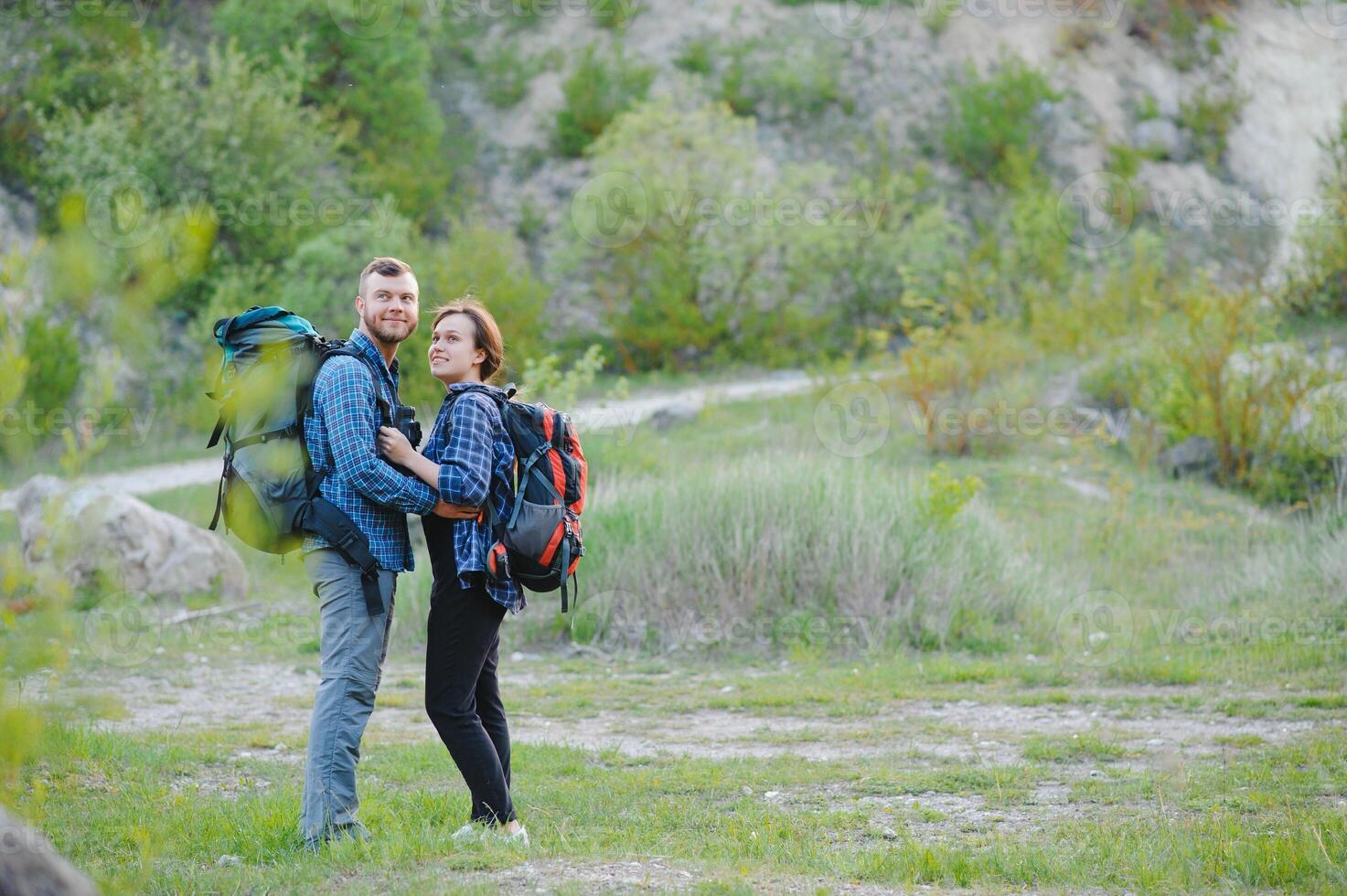 une couple de touristes dans temps de voyage acier et admirer le magnifique Montagne paysage. le gars câlins le fille. le concept de aimer, tendresse et des loisirs photo