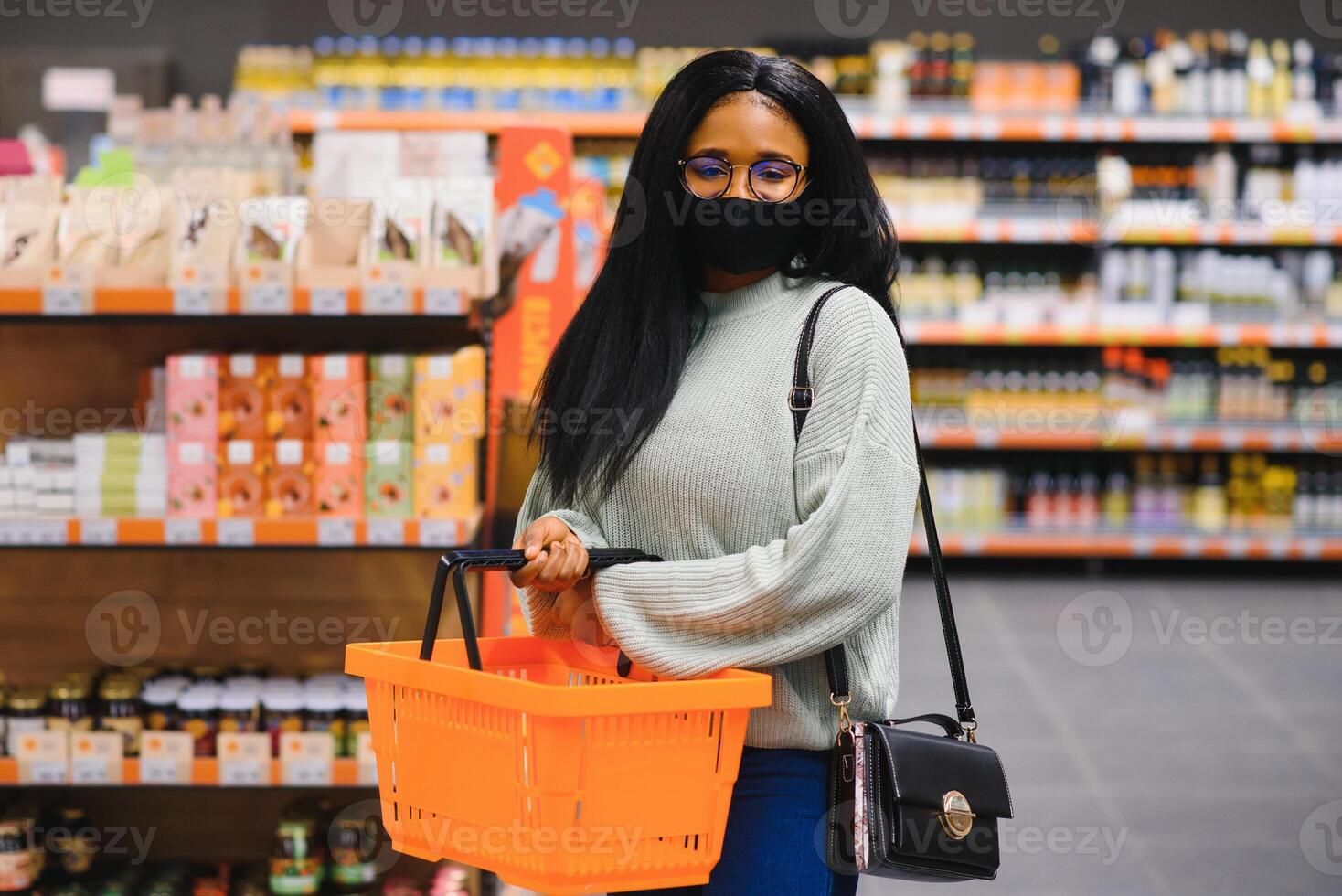 africain femme portant jetable médical masque achats dans supermarché pendant coronavirus pandémie épidémie. épidémie temps photo