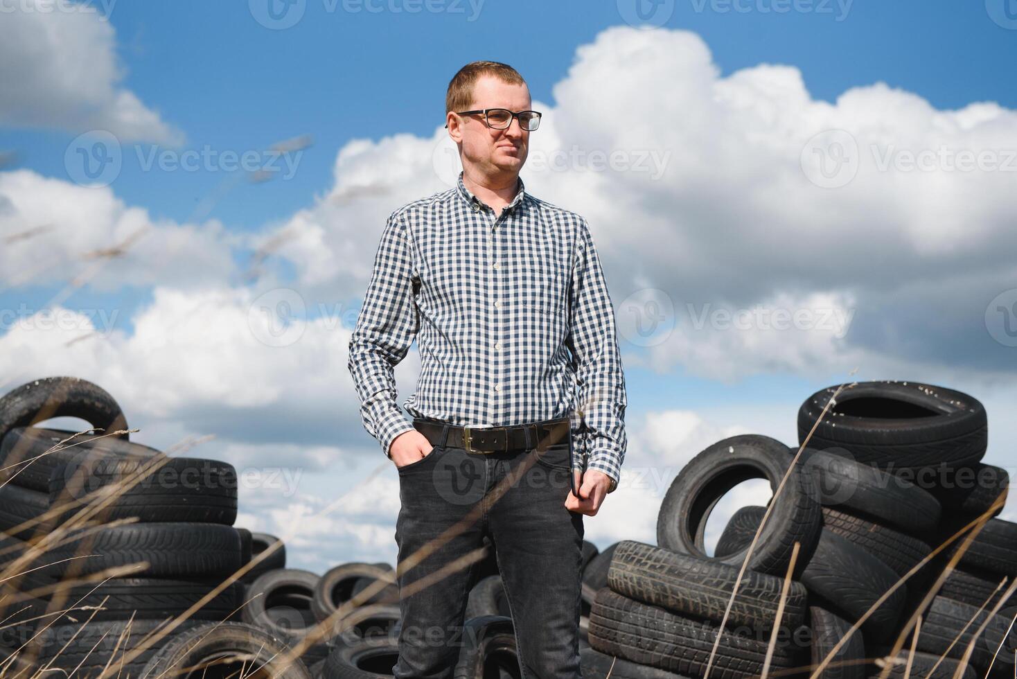 éco-activiste à le décharge de utilisé voiture pneus calcule environnement dommage. la nature préservation concept photo