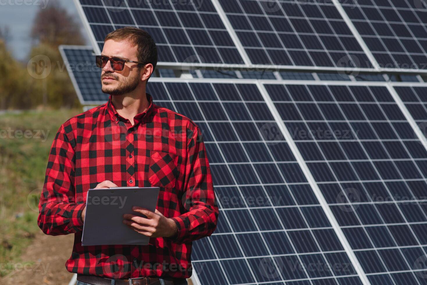 portrait de homme avec une tablette dans le sien mains permanent près le solaire panneaux gare. vert écologique Puissance énergie génération. solaire station développement concept. Accueil construction. photo