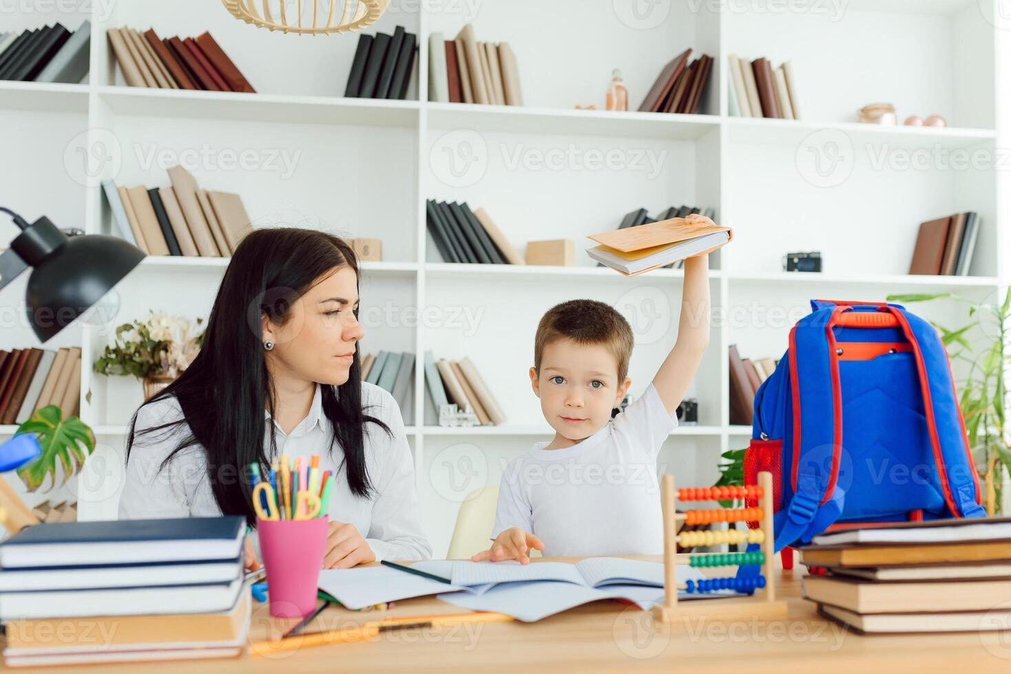 femelle privé tuteur portion Jeune étudiant avec devoirs à bureau dans brillant enfant pièce photo