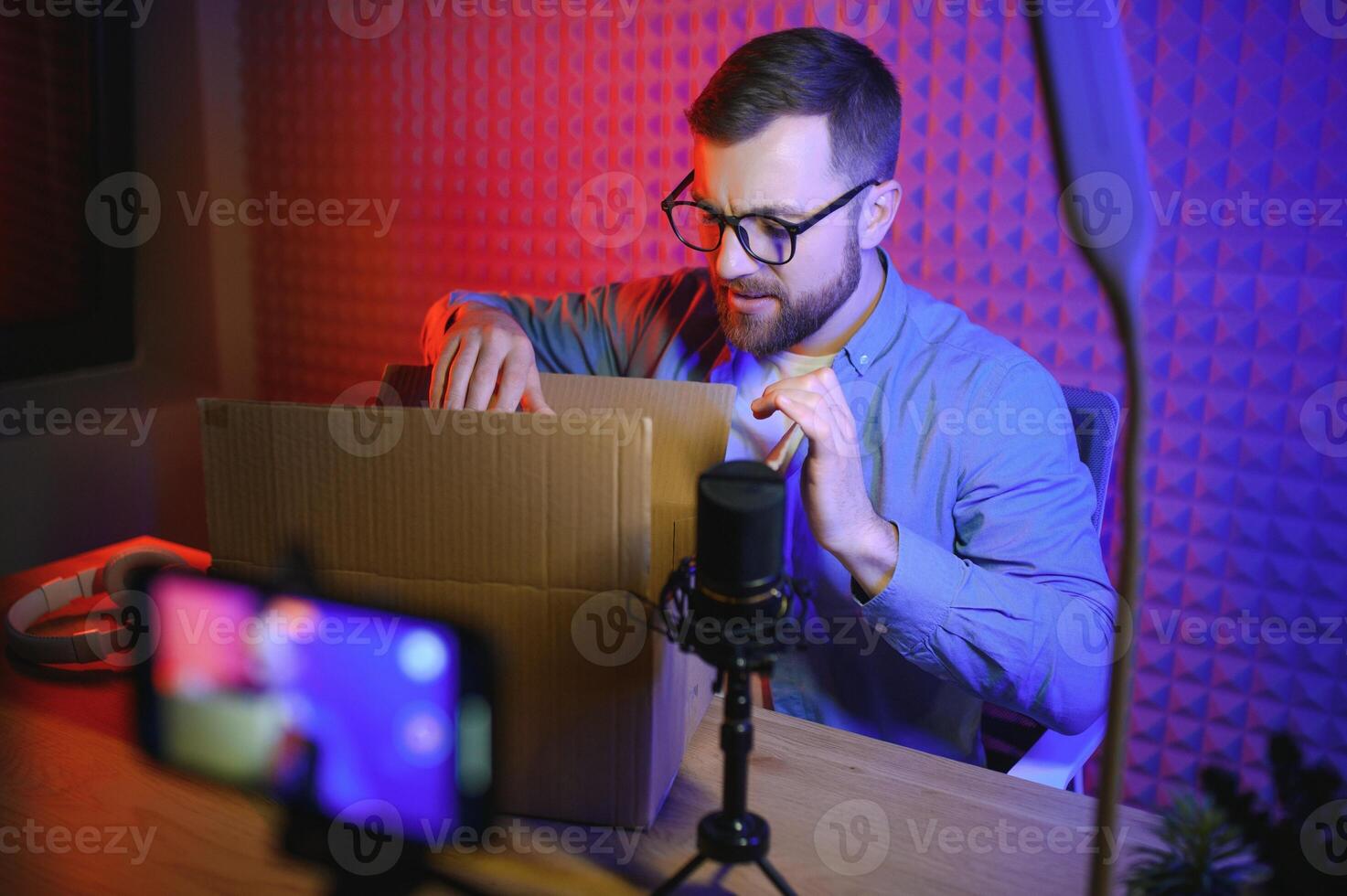 Beau Jeune homme faire des gestes tandis que déballage colis, excité, serre les poings dans triomphe. joyeux Masculin vlogger. concept de gens et social réseaux. photo