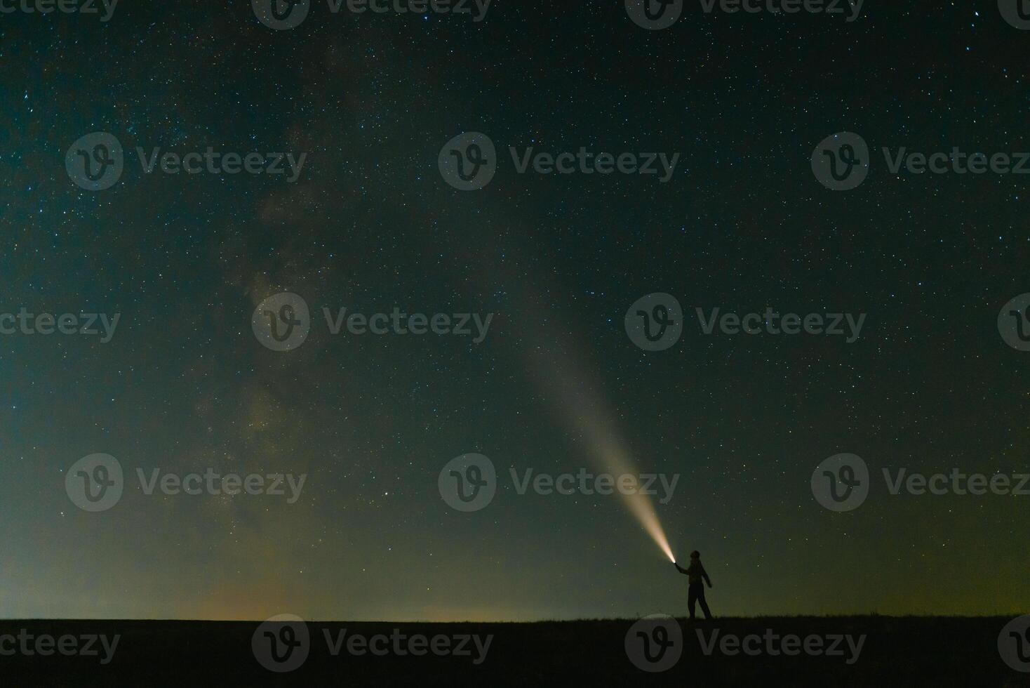 retour vue de homme avec tête lampe de poche permanent sur vert herbeux champ en dessous de magnifique foncé bleu été étoilé ciel. nuit la photographie, beauté de la nature concept. large panorama, copie espace Contexte. photo