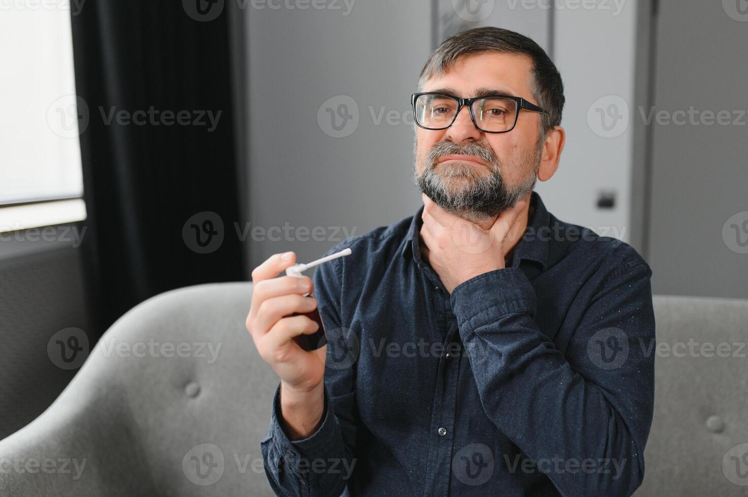 malade Sénior homme en utilisant gorge vaporisateur à Accueil photo