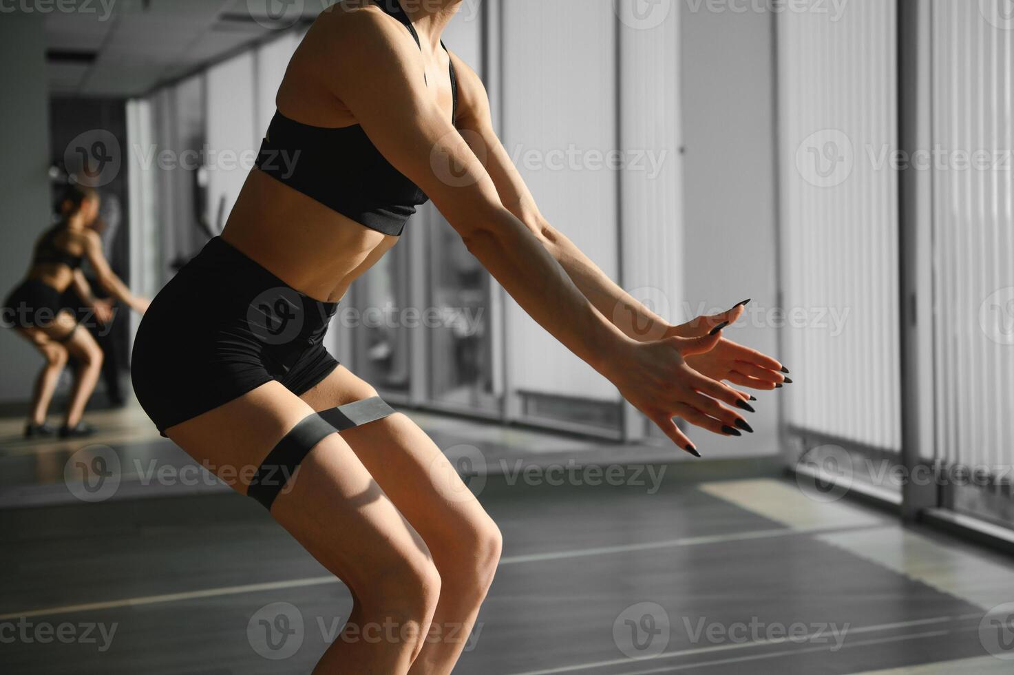 crossfit en bonne santé mode de vie concept. agréable charmant adorable magnifique sportif musclé aptitude modèle Dame portant des sports culotte et Haut avec noir élastique bande sur jambes muscles Faire redressements assis photo