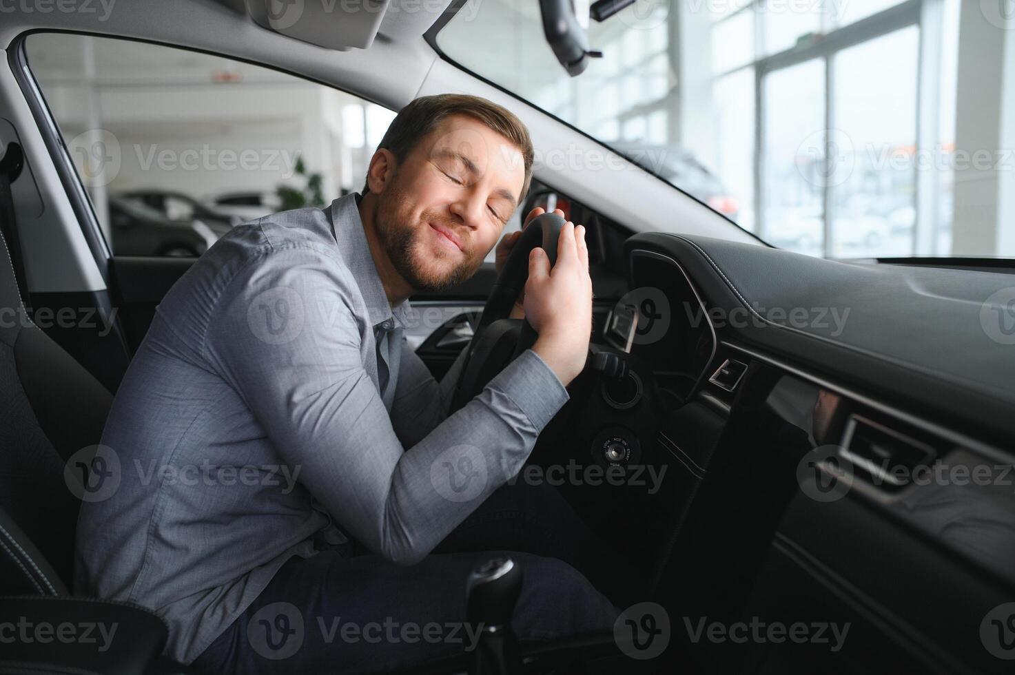 visite voiture concession. Beau barbu homme est caressant le sien Nouveau voiture et souriant. photo