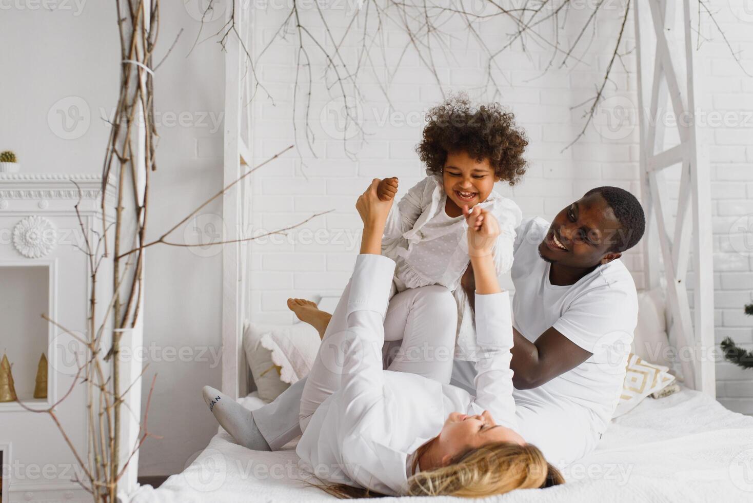 excité multiracial Jeune famille avec peu fille enfant avoir amusant, fou de joie heureux. international maman et papa jouer avec petit fille, prendre plaisir fin de semaine à Accueil ensemble photo