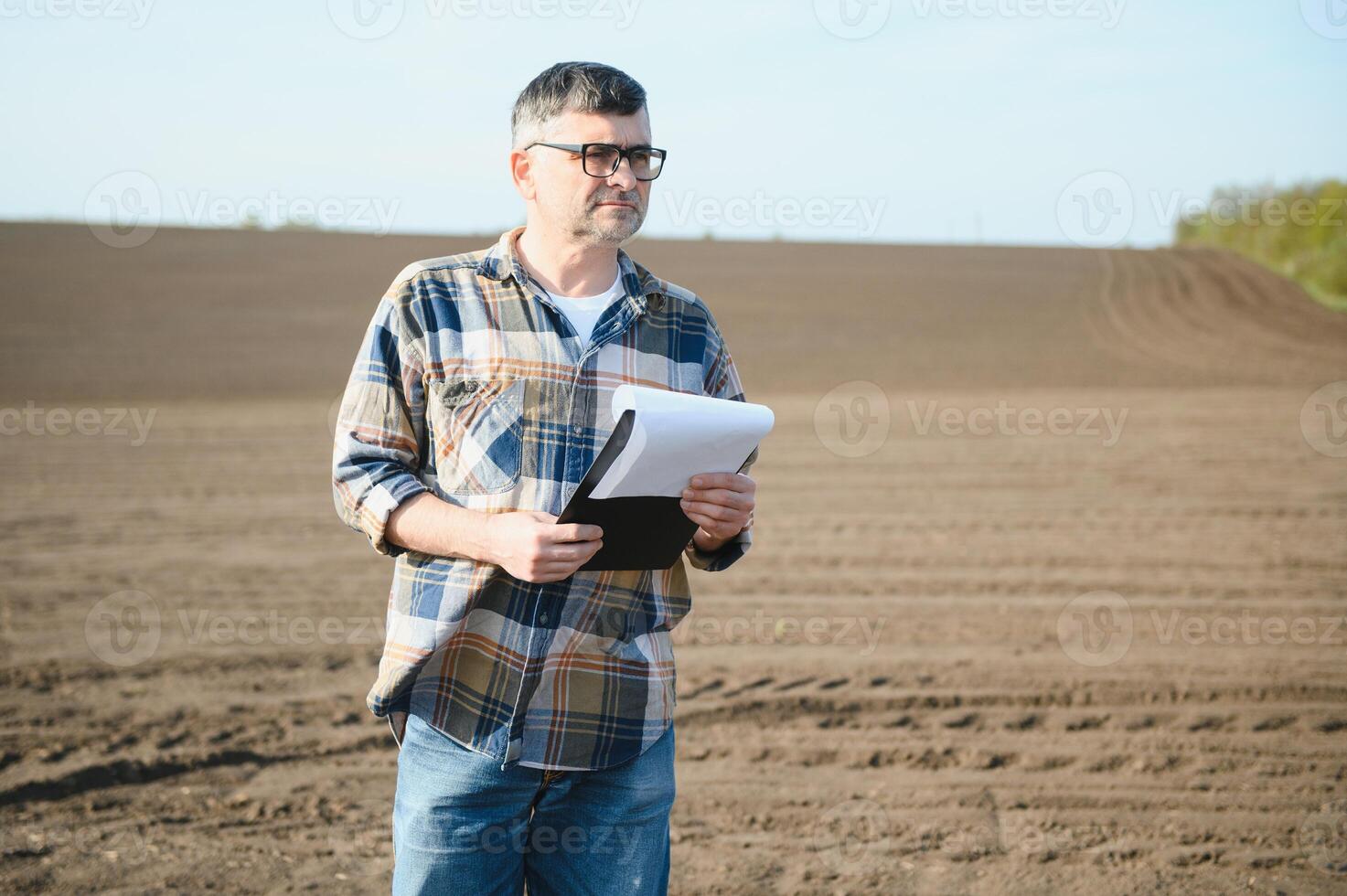 le agriculteur travaux sur le sol. Masculin agriculteur sur une labouré champ, plantation céréales dans le printemps dans le sol. agricole affaires concept. croissance nourriture, des légumes. photo