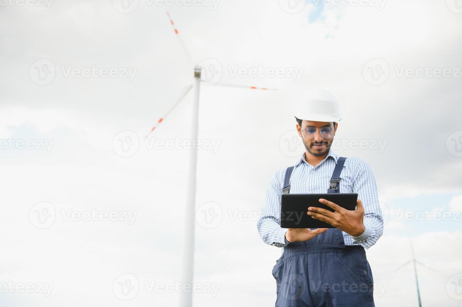 Inde ingénieur à Moulin à vent ferme opération à produire électricité, asiatique homme travail à vent turbine cultiver, nettoyer et vert énergie. photo