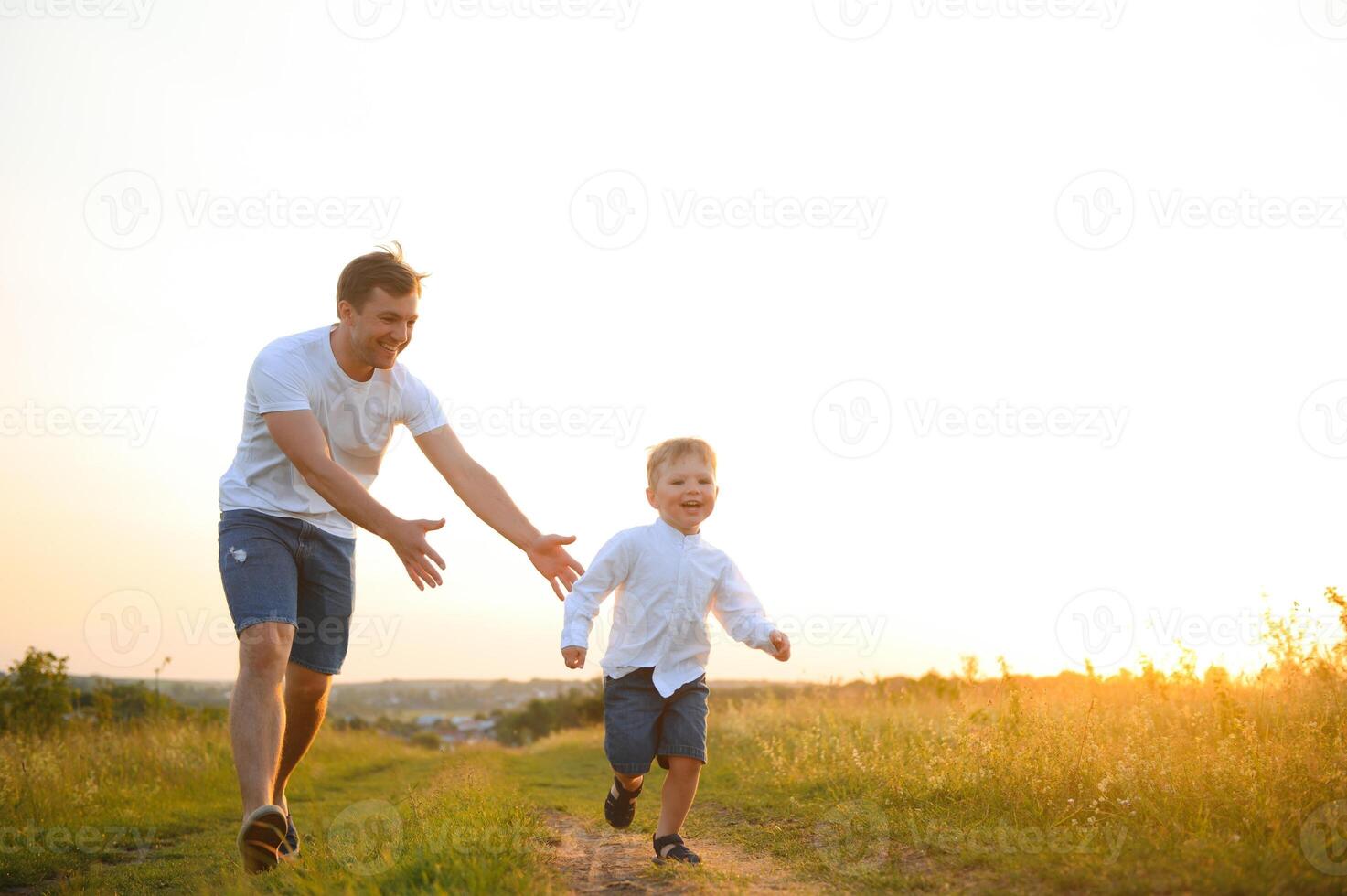 du père journée. content famille père et bambin fils en jouant et en riant sur la nature à le coucher du soleil photo