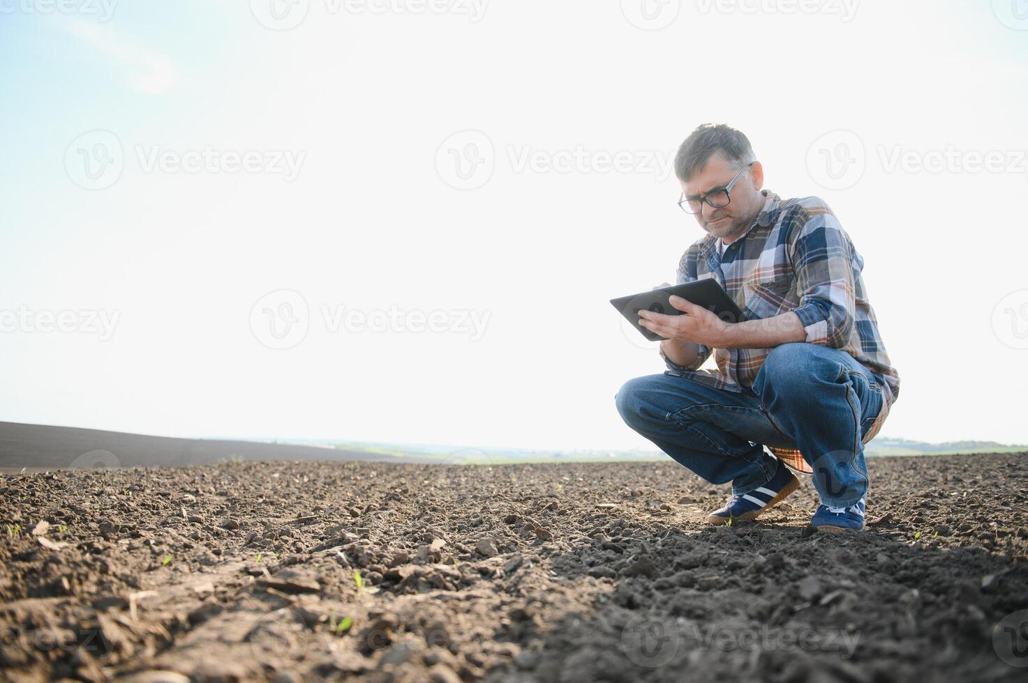 le agriculteur travaux sur le sol. Masculin agriculteur sur une labouré champ, plantation céréales dans le printemps dans le sol. agricole affaires concept. croissance nourriture, des légumes. photo