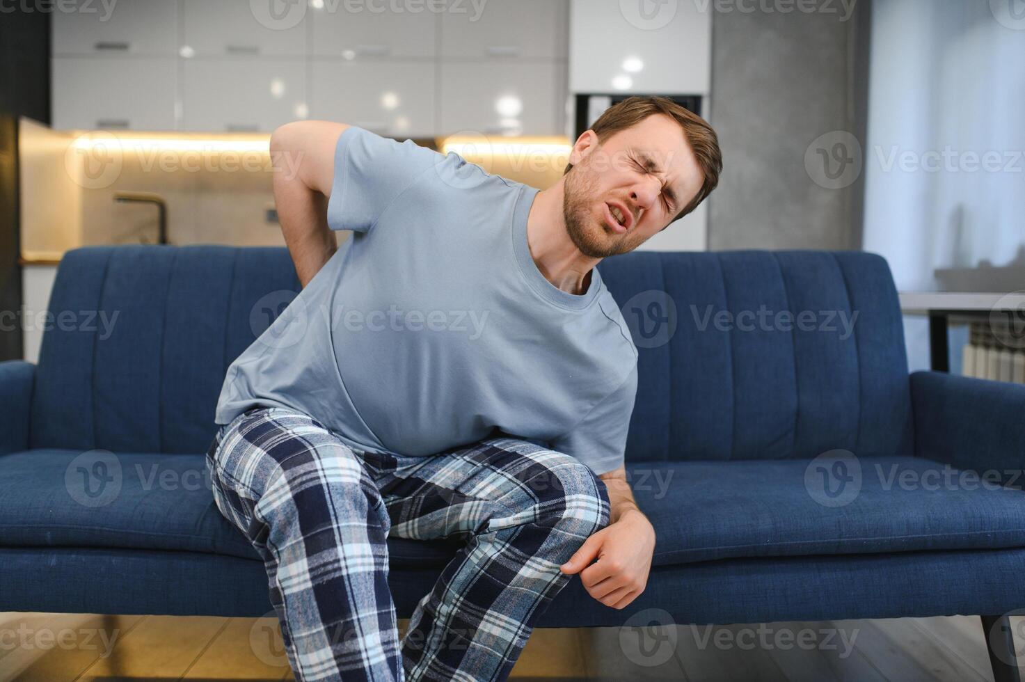 personnes, soins de santé et traitement. portrait de malade homme Souffrance de aigu côté retour douleur, séance sur canapé à maison, la personne émouvant inférieur retour douloureux zone avec main. santé problème concept photo