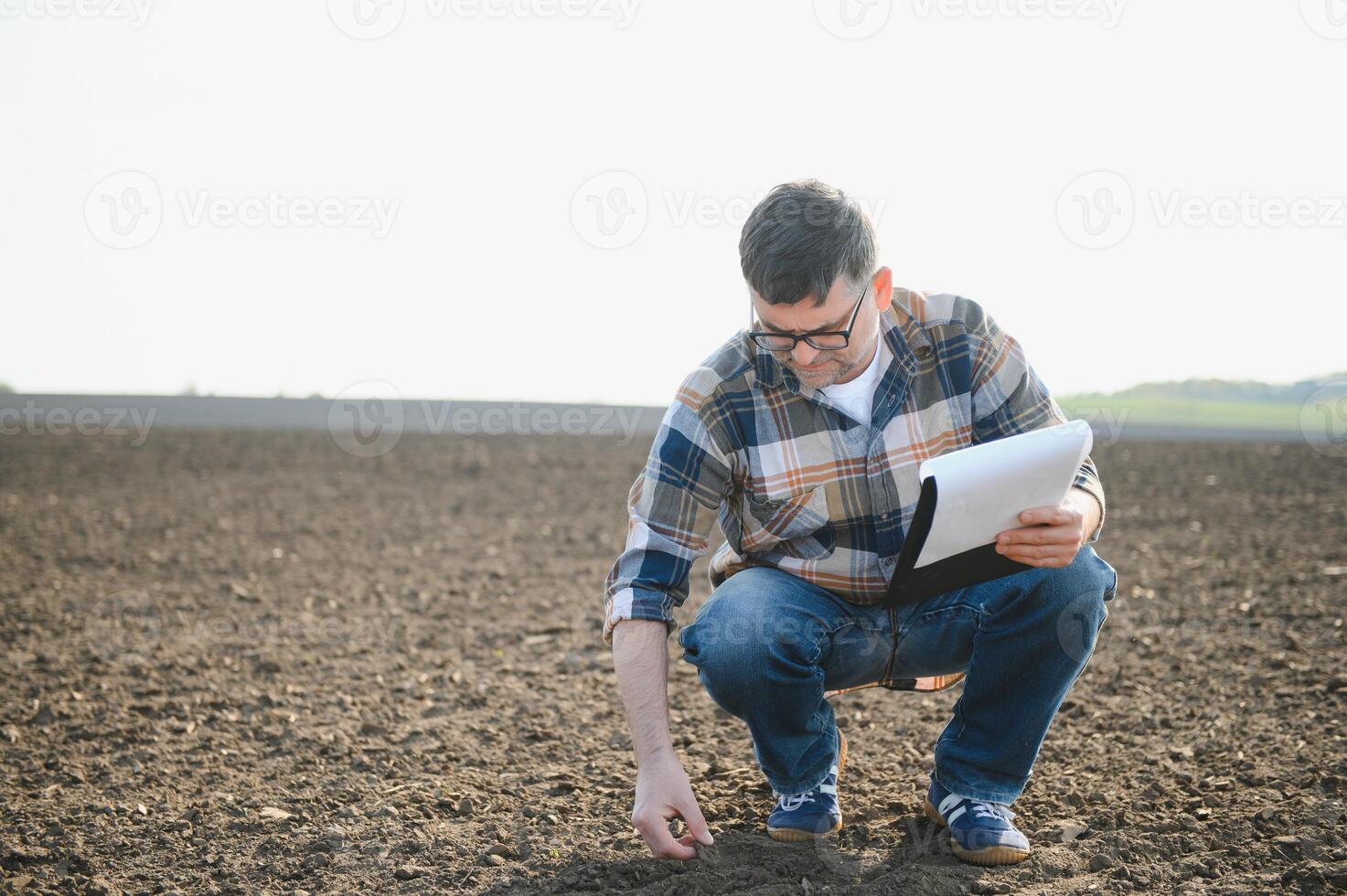 une Jeune agriculteur inspecte le qualité de blé choux dans le champ. le concept de agriculture. photo