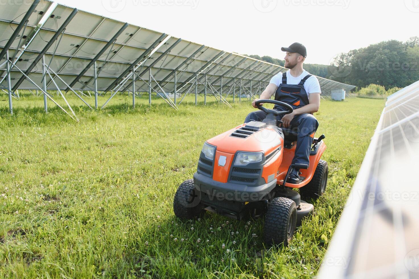 une homme tond le herbe près le solaire panneaux. vert énergie photo