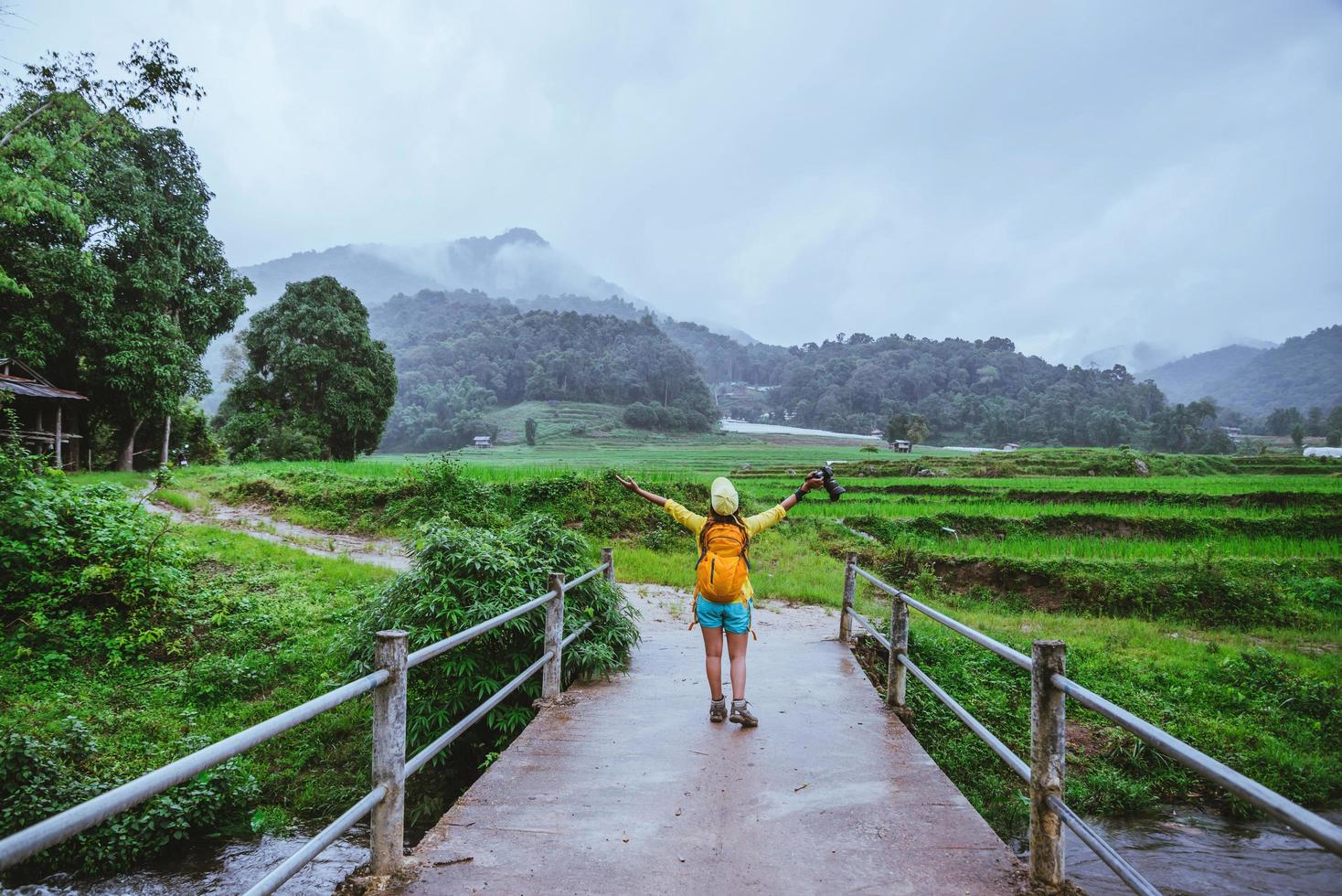 les femmes asiatiques voyagent dans la nature. marcher une photo la rizière et arrêter faire une pause se détendre sur le pont à ban mae klang luang en saison des pluies.