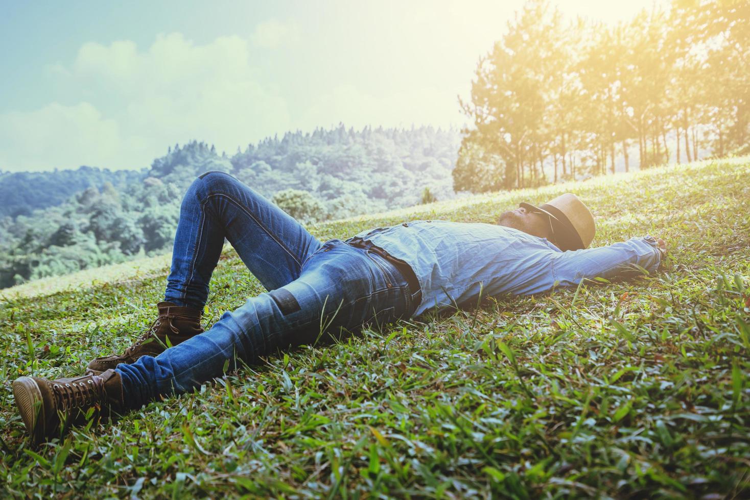 voyage homme asiatique se détendre pendant les vacances. dormir se détendre sur la pelouse sur la montagne. en Thaïlande photo