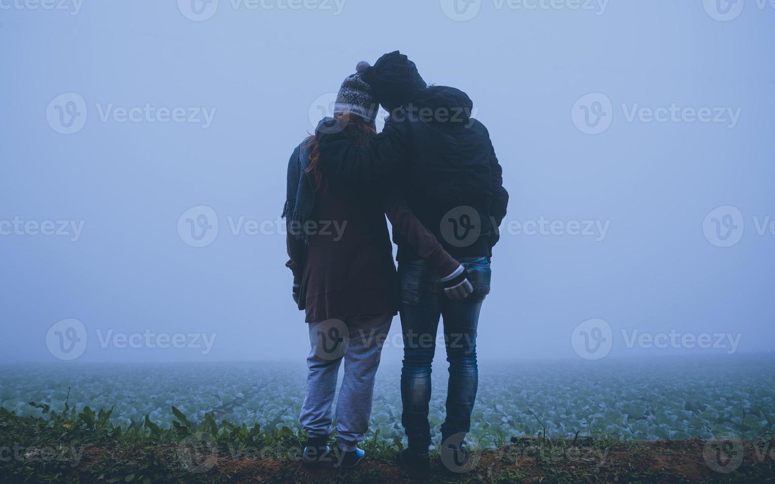 amoureux des femmes et des hommes asiatiques voyagent se détendre pendant les vacances. heureux de voyager pendant les vacances. les amoureux marchent main dans la main sur une rizière. pendant l'hiver brumeux photo