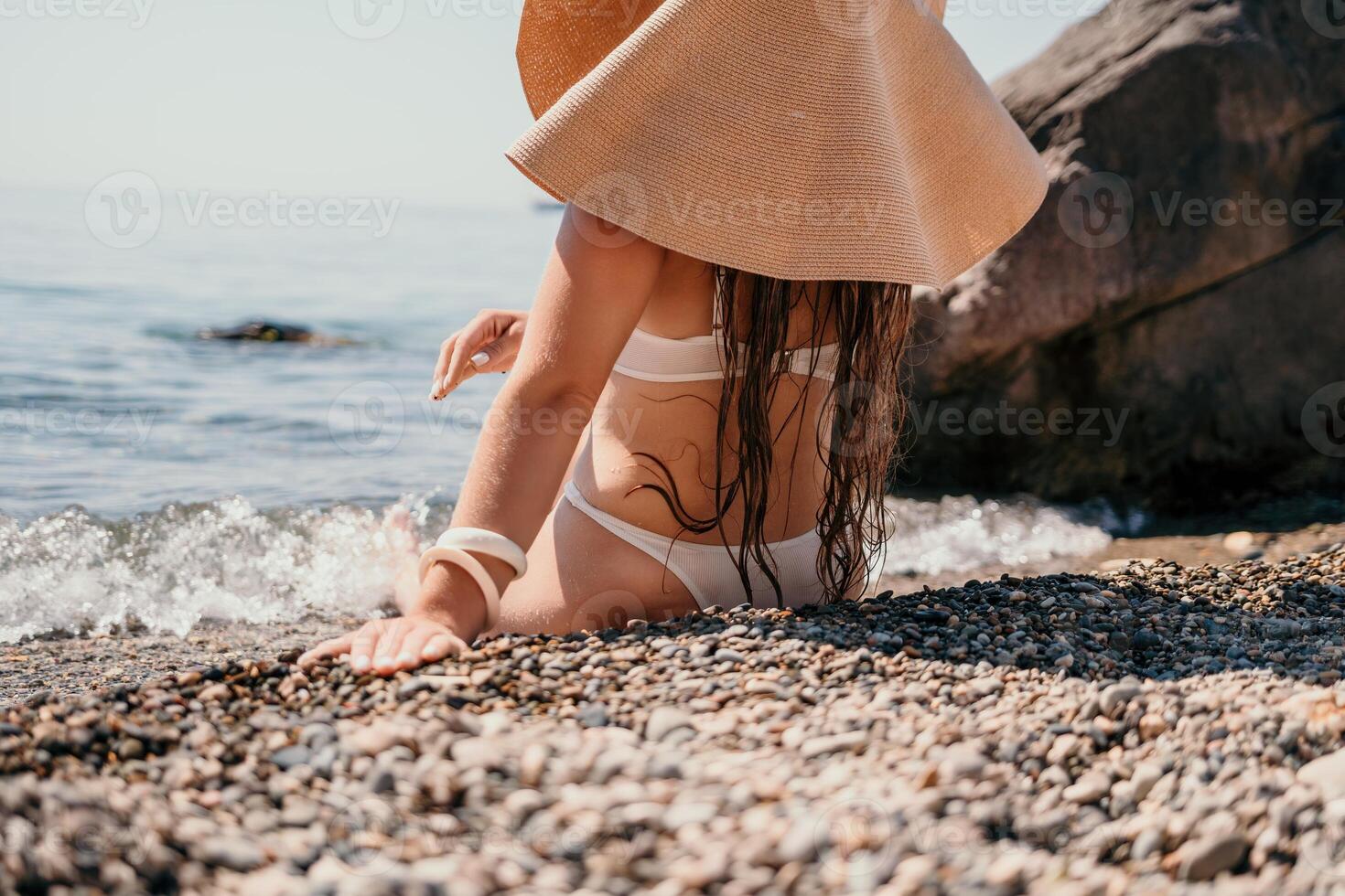 femme Voyage mer. content touristique dans chapeau prendre plaisir prise image en plein air pour souvenirs. femme voyageur posant sur le plage à mer entouré par volcanique montagnes, partage Voyage aventure périple photo