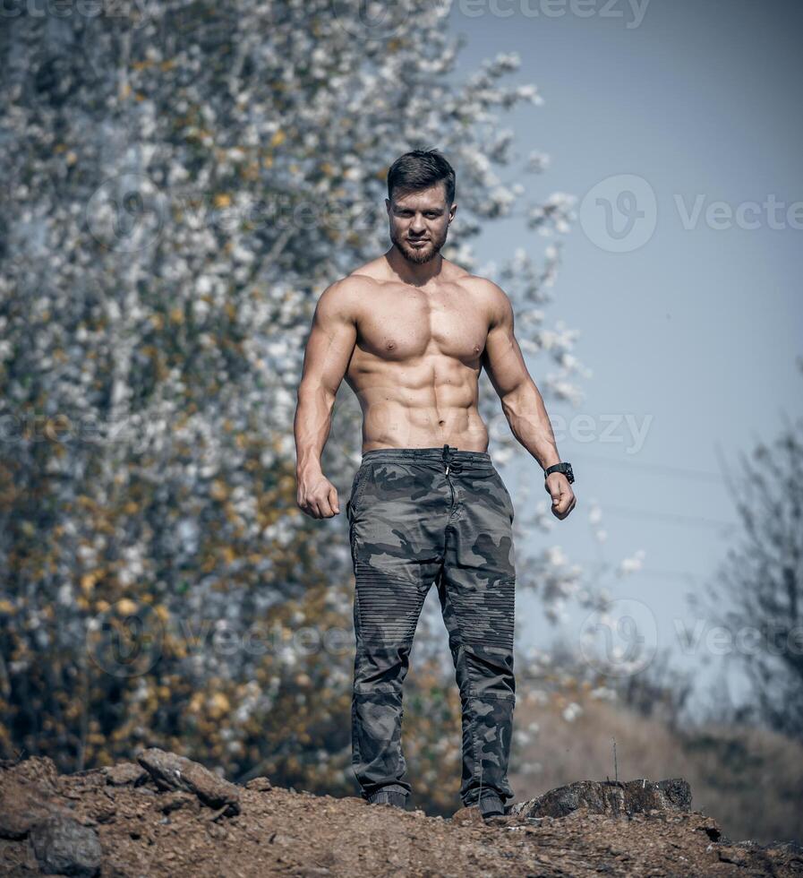 homme dans militaire un pantalon permanent sur la nature Contexte. parfait Masculin corps. photo