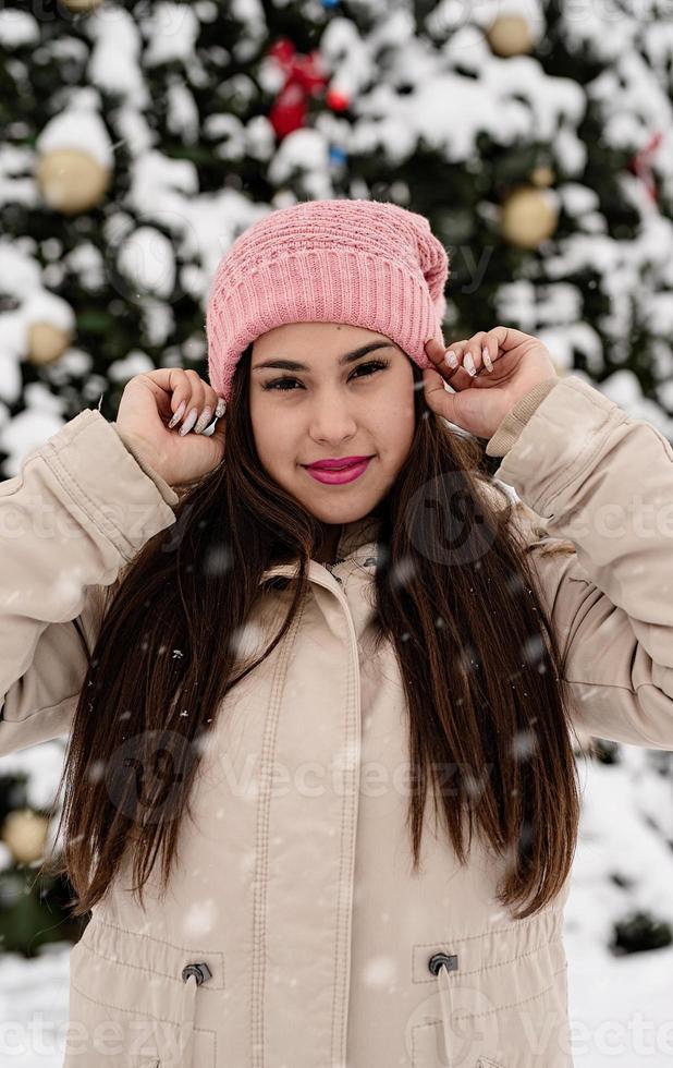 portrait d'une femme dans des vêtements d'hiver chauds debout près du grand arbre de noël à l'extérieur photo