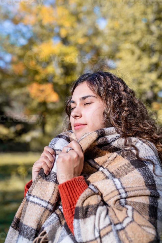 Portrait de jeune femme heureuse en plaid chaud dans la forêt d'automne photo