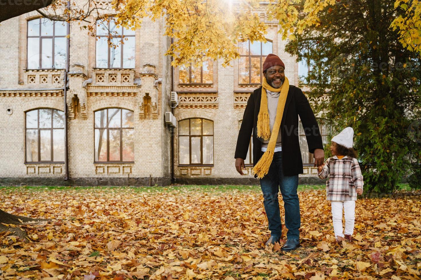 grand-père et petite-fille noirs s'amusant en jouant ensemble dans un parc d'automne photo