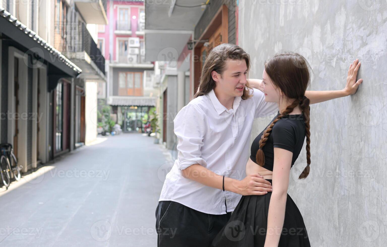 une couple est profiter une été vacances dans le communauté des rues, Heureusement montrant leur l'amour à chaque autre. photo