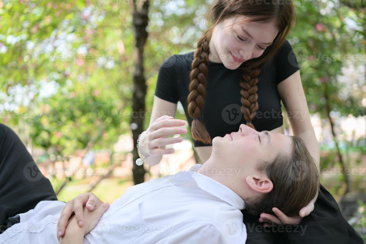 une couple est profiter une été vacances dans le parc, Heureusement montrant leur l'amour à chaque autre. photo