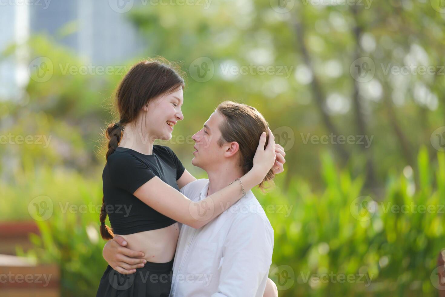 une couple est profiter une été vacances dans le parc, Heureusement montrant leur l'amour à chaque autre. photo