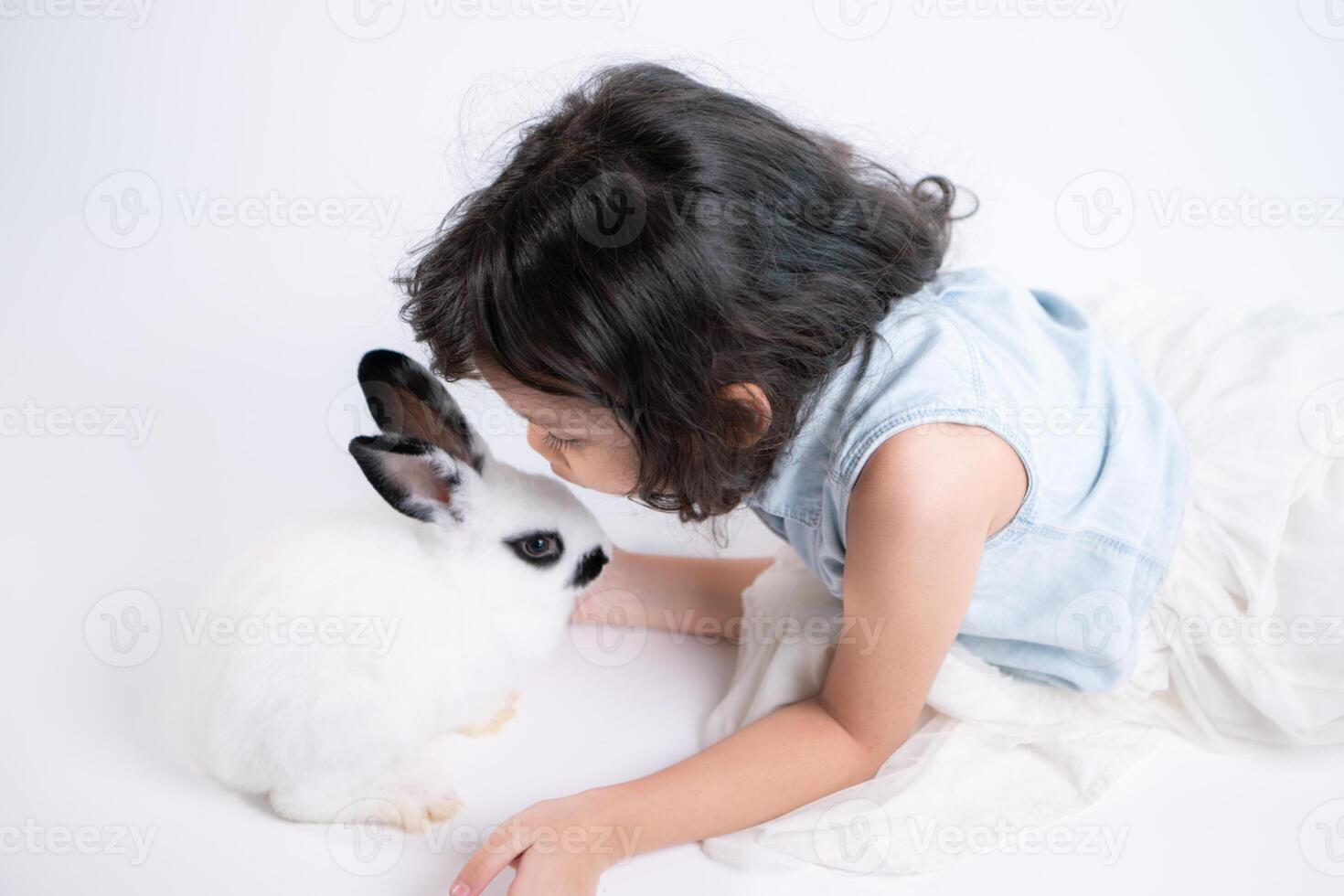 une peu fille baisers sa bien-aimée duveteux lapin, le beauté de relation amicale entre humains et animaux photo