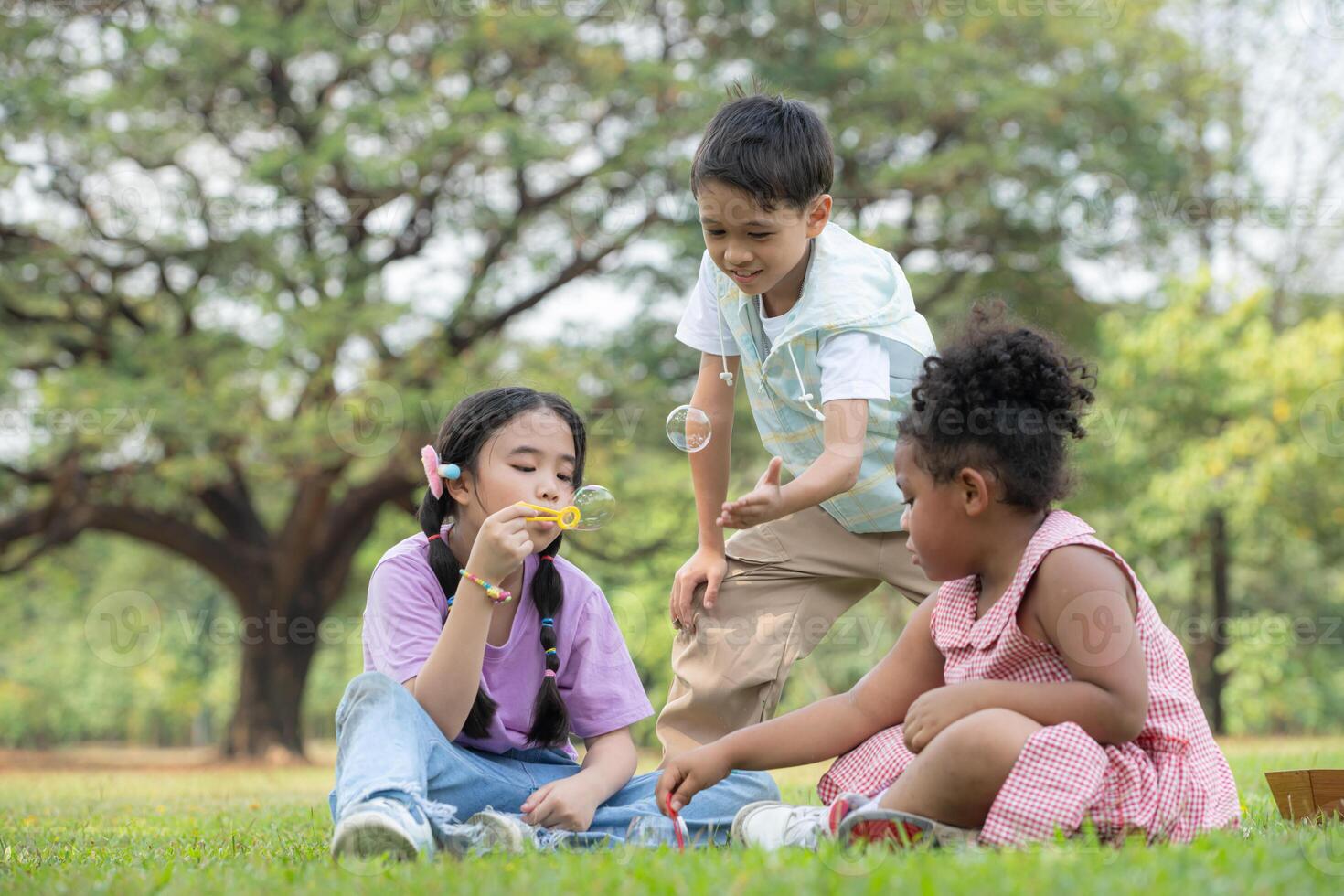 les enfants séance dans le parc avec soufflant air bulle, entouré par verdure et la nature photo