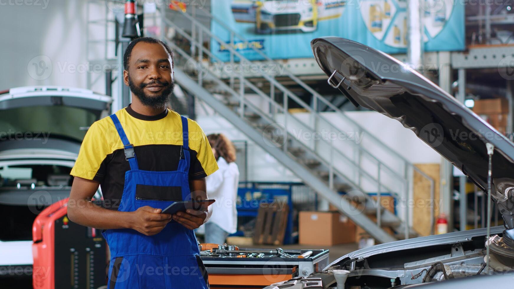 portrait de souriant mécanicien dans voiture un service commande Nouveau les pièces pour endommagé véhicule en utilisant tablette. africain américain dépanneur à la recherche en ligne pour Composants à remplacer vieux ceux dans cassé voiture photo