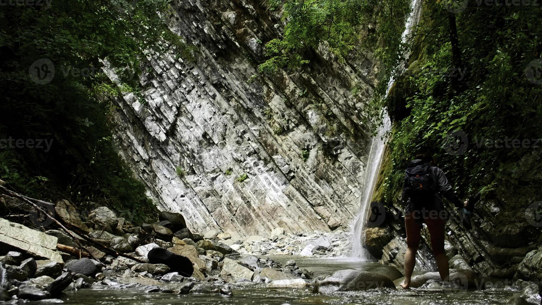 femme traversée Montagne du froid l'eau courant avec des pierres. créatif. promeneur dans pittoresque lieu. photo