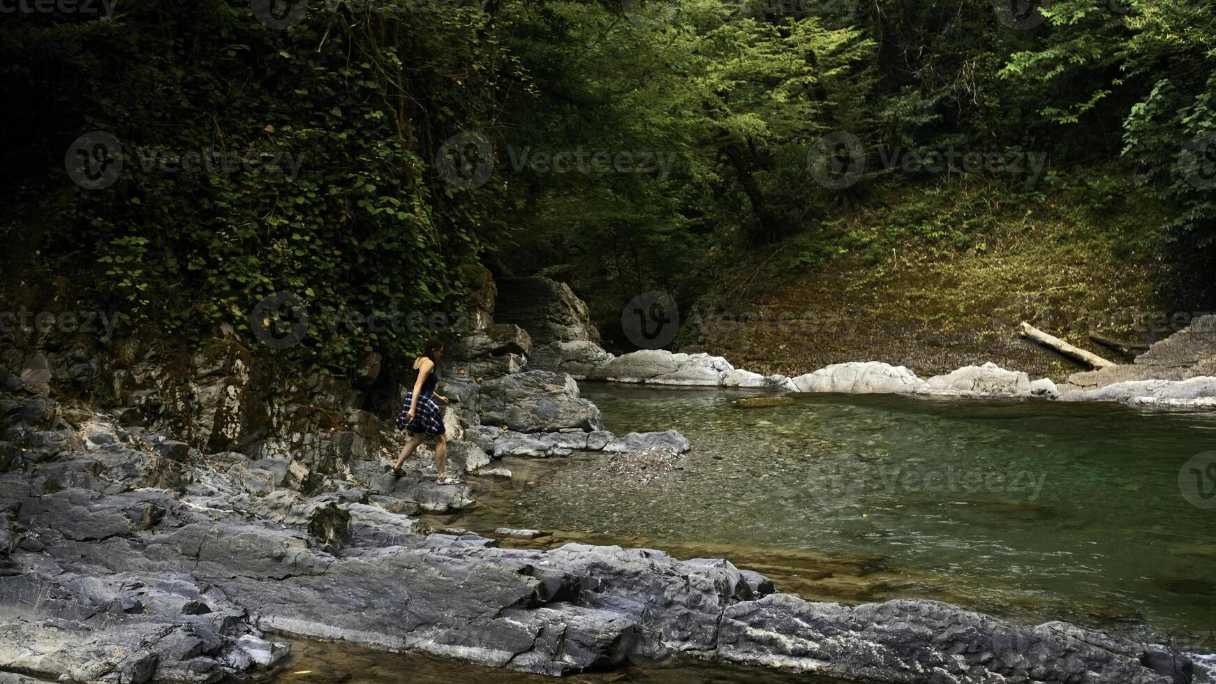 homme en marchant sur le rocheux rivière dans paradis lieu. créatif. femme refroidissement sa pieds dans cld Montagne flux. photo