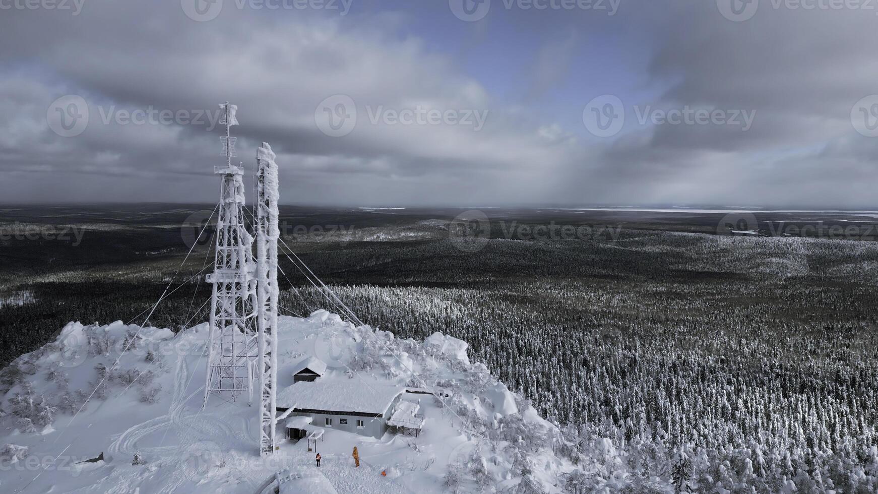 congelé répétiteur antenne sur le Haut de une colline dans l'hiver. agrafe. aérien vue de hiver vallée panorama et bleu nuageux ciel. photo