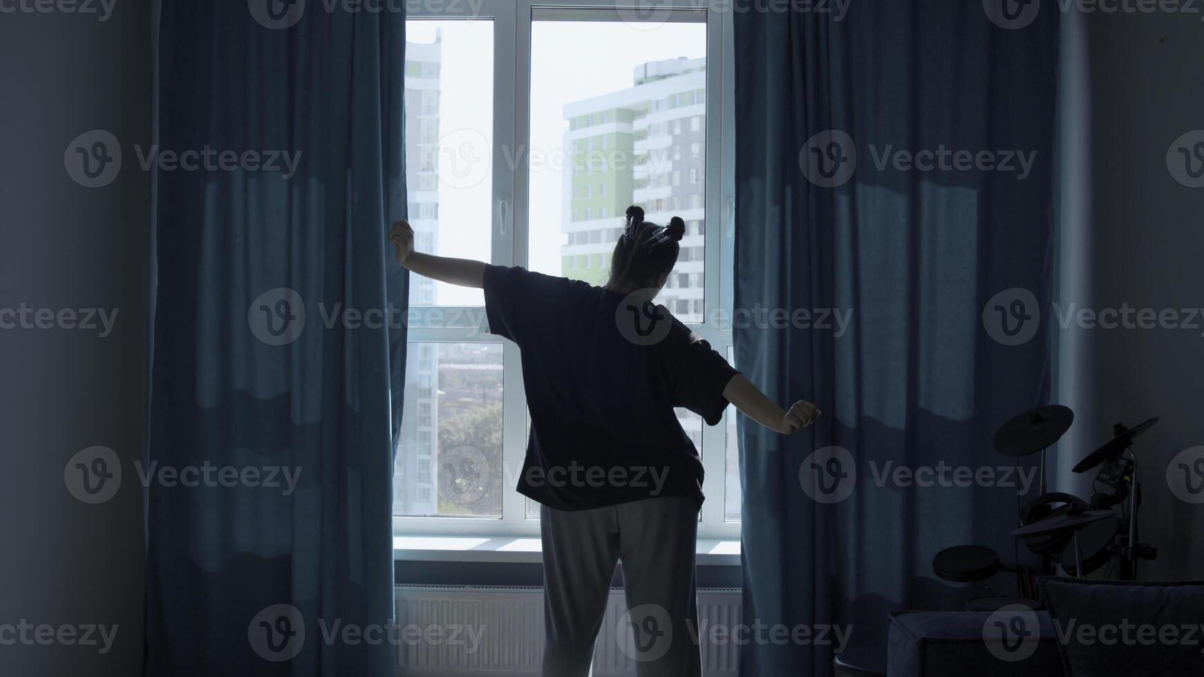 arrière vue de une femme tirant une fenêtre rideaux pour Matin lumière. médias. Jeune femme ouverture rideaux dans une chambre et élongation après dormir. photo