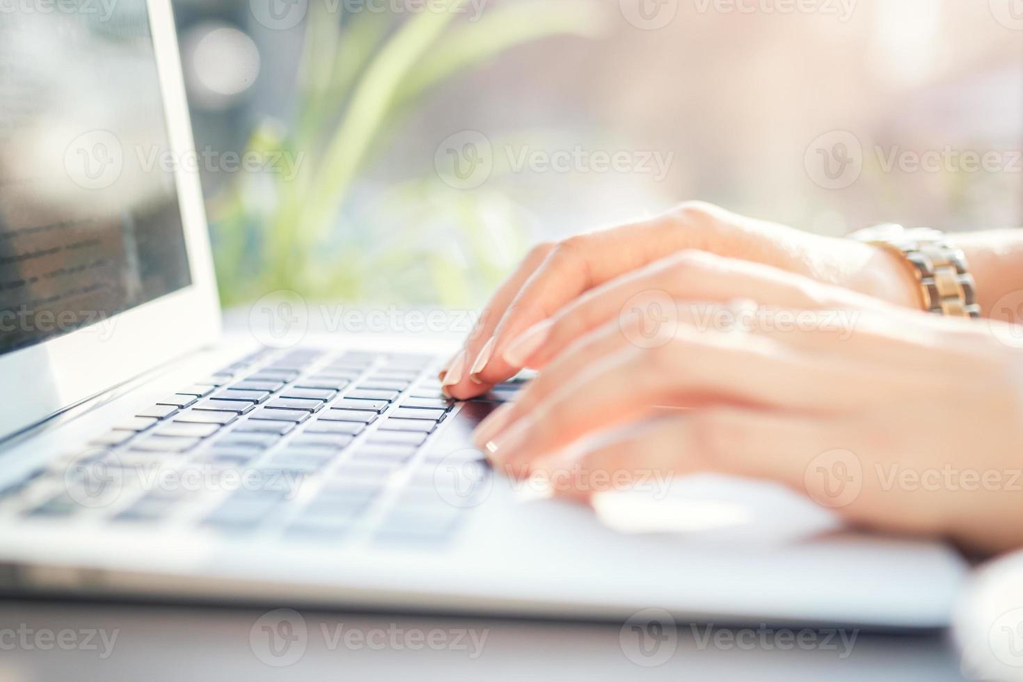 une employée de bureau tape le texte sur le clavier. fille travaillant sur ordinateur portable photo