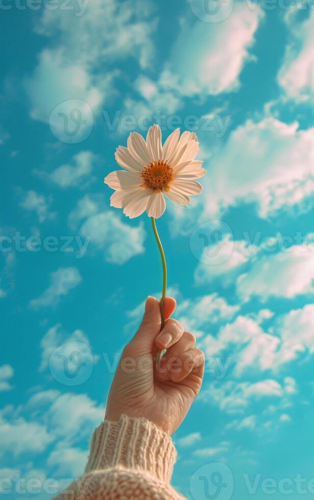 ai généré une main ascenseurs une Célibataire fleur vers une vibrant bleu ciel à pois avec des nuages photo