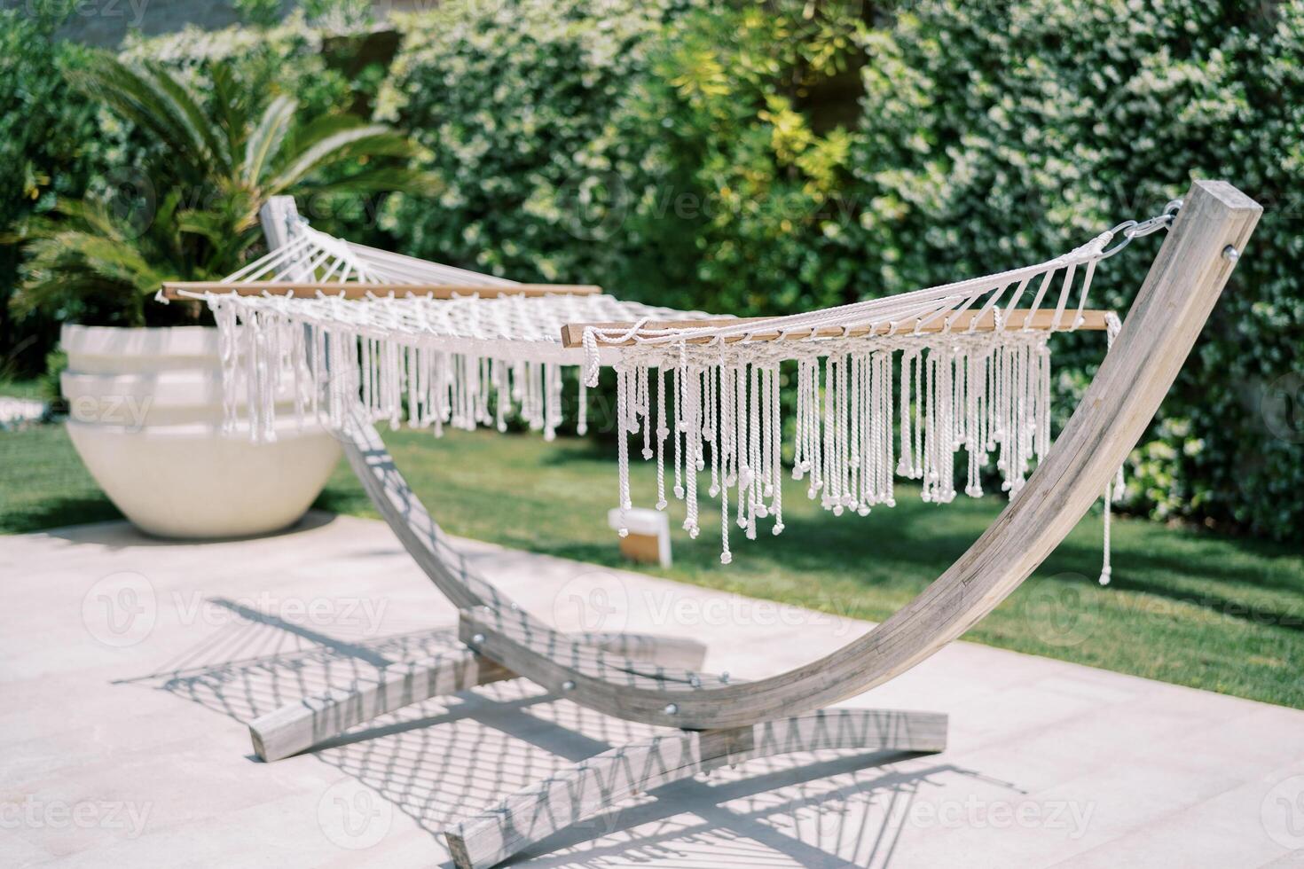 blanc osier hamac avec pompons bloque sur une en bois supporter dans une vert jardin photo