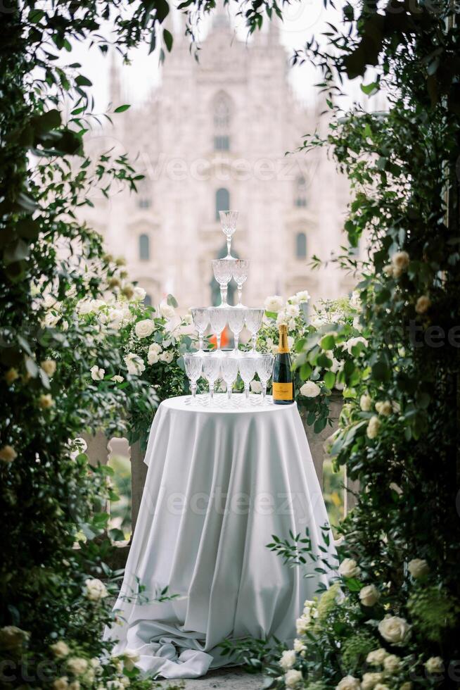 empiler de des lunettes sur une table suivant à une bouteille de Champagne sur une balcon couvert avec des roses surplombant le duomo. milan, Italie photo