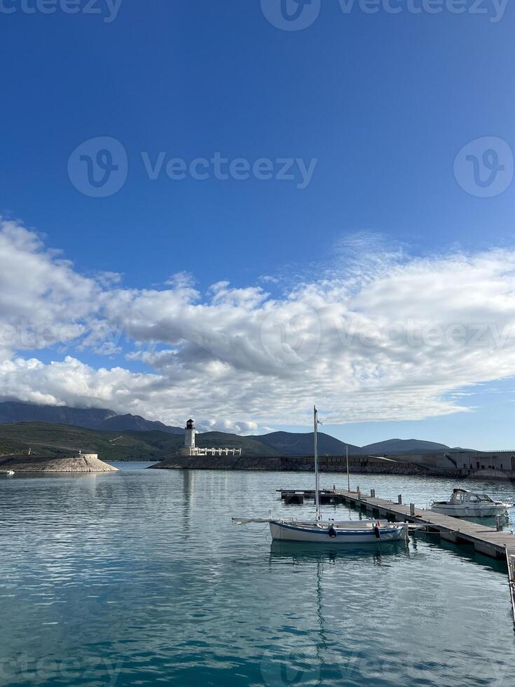 bateaux amarré à le jetée contre le toile de fond de une phare à le pied de le montagnes photo