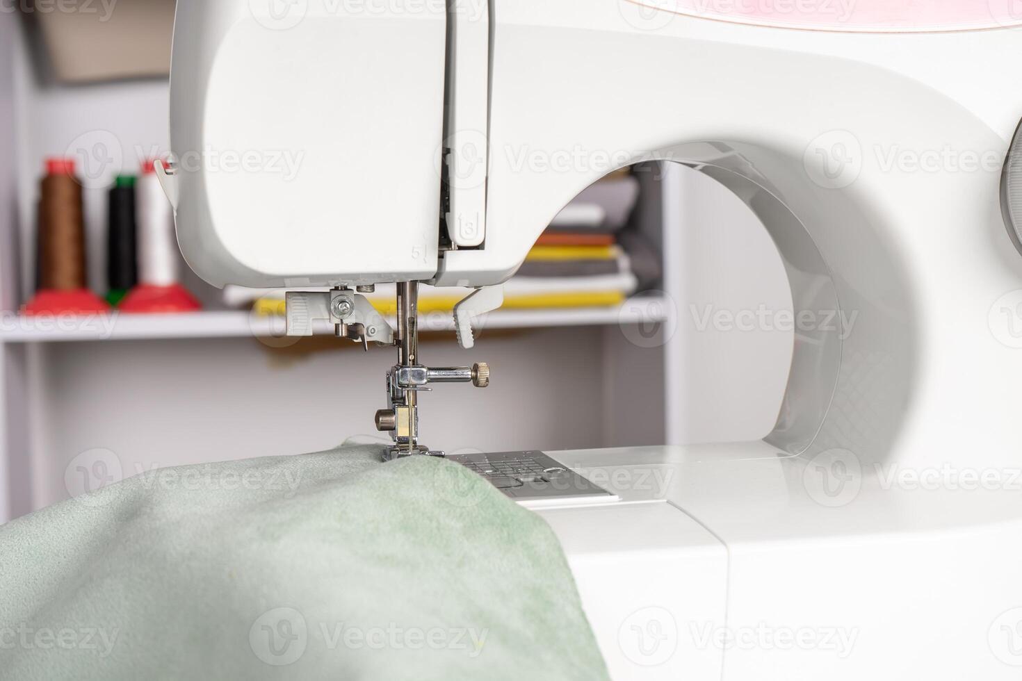 moderne couture machine presseur pied avec vert en tissu et fil photo