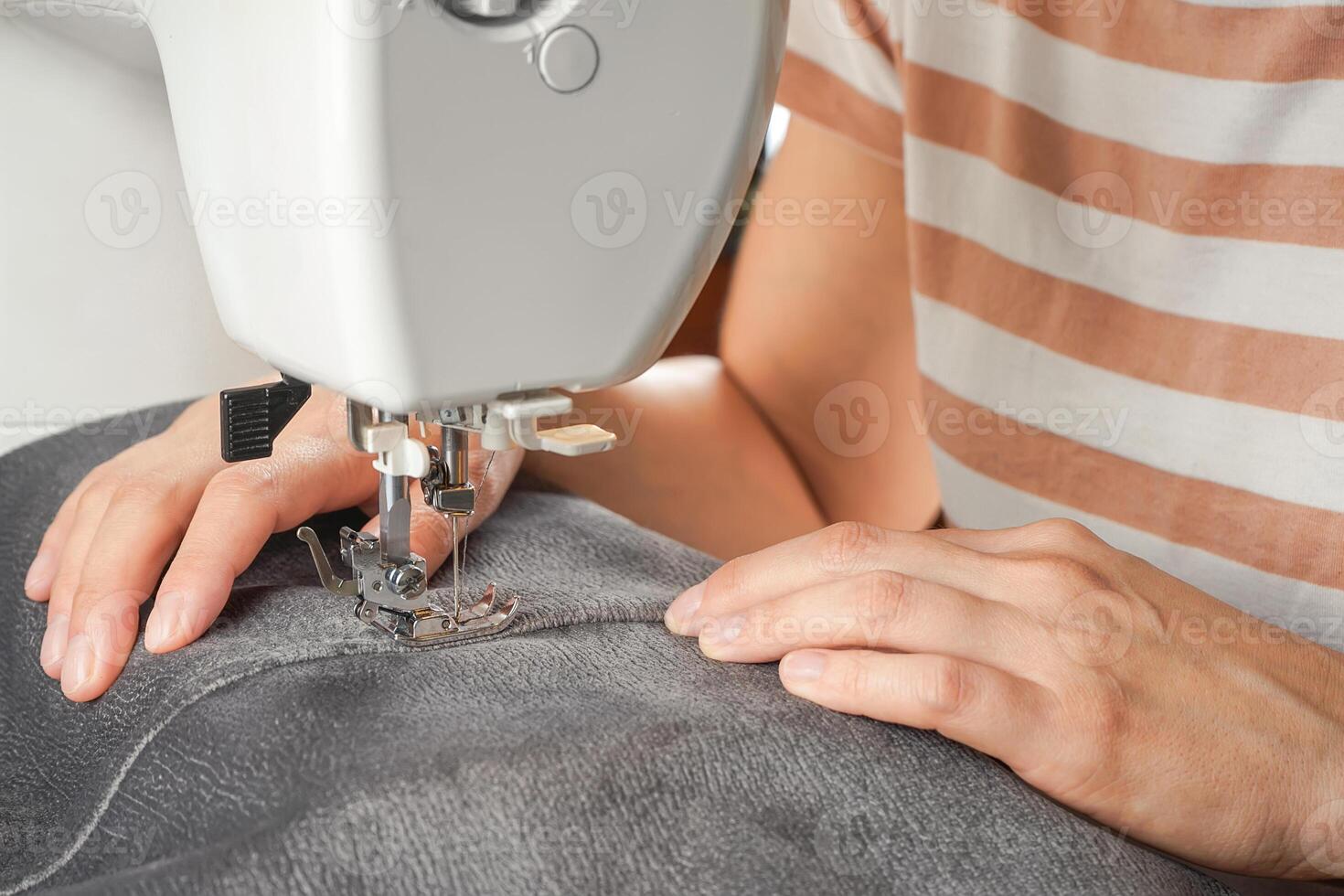 tailleur mains piqûre gris en tissu sur moderne couture machine à lieu de travail dans atelier photo