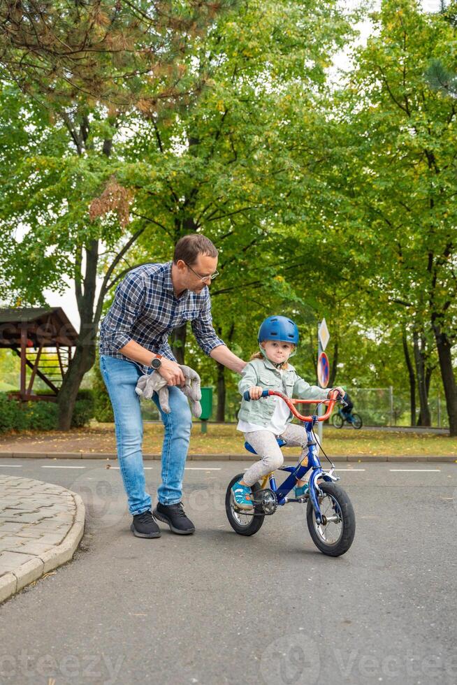 Jeune père enseigne enfant fille à balade Publique bicyclette sur circulation terrain de jeux dans Prague, tchèque république, L'Europe . haute qualité photo