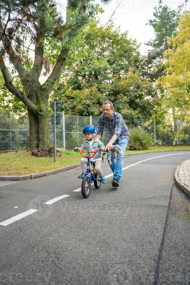 content famille père enseigne enfant fille à balade Publique bicyclette sur un de circulation Cour de récréation, Prague, tchèque république, L'Europe . haute qualité photo