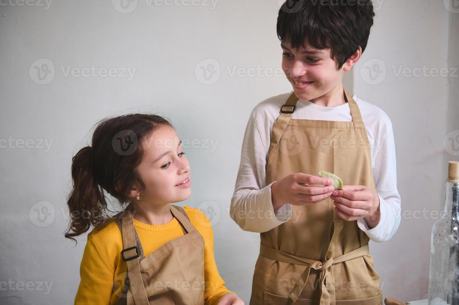 authentique portrait de adorable des gamins dans beige chef tablier, fabrication Dumplings à Accueil cuisine photo